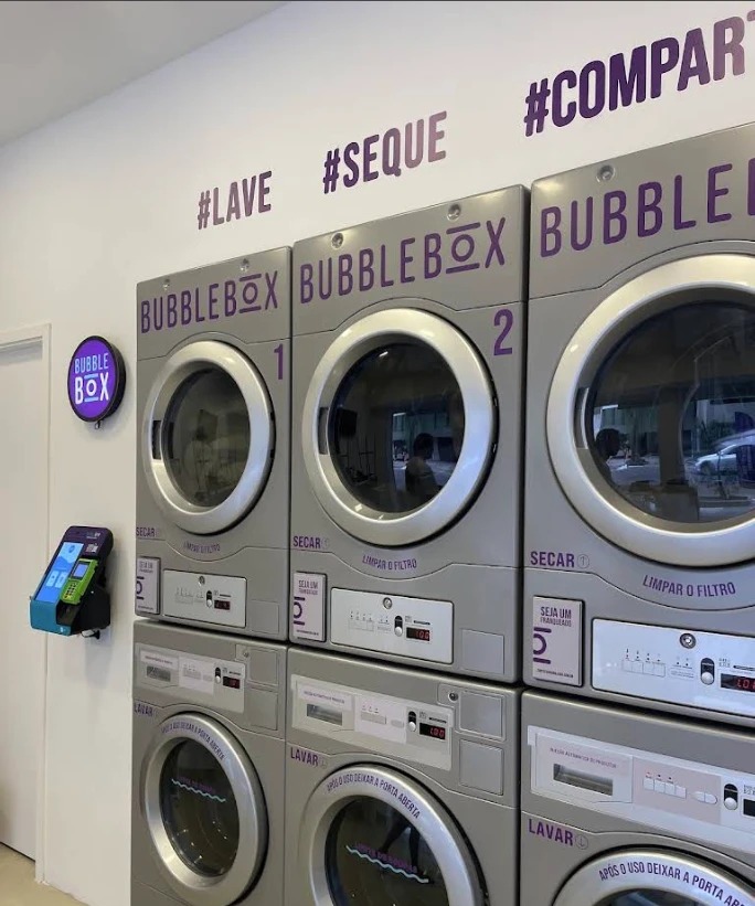 Lavadoras e secadoras da Bubble Box Niterói sob o painel #Lave #Seque #Compartilhe