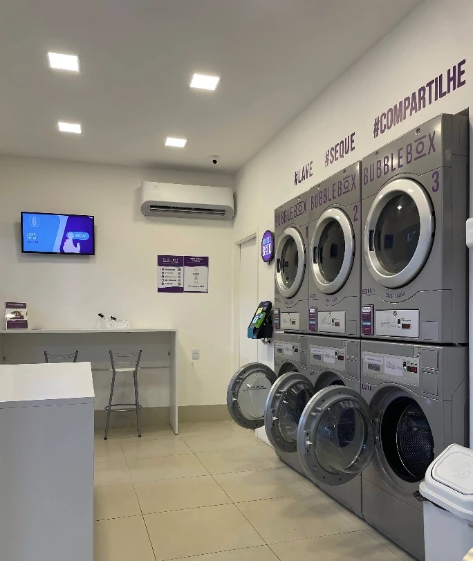 Área de espera da Bubble Box Niterói com bancada, banquetas e TV